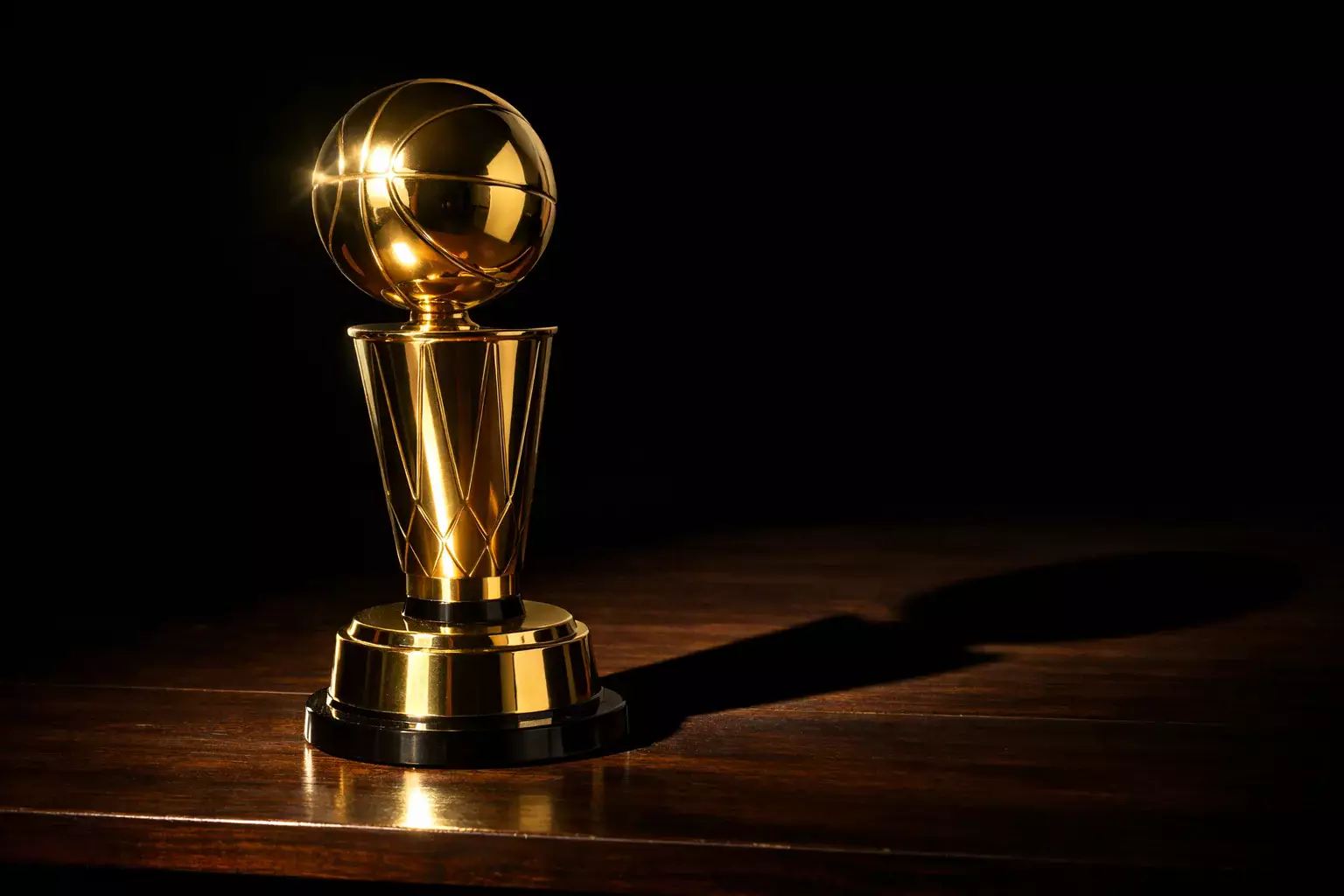 Trofeo dorado de baloncesto sobre una mesa con luz dramática lateral